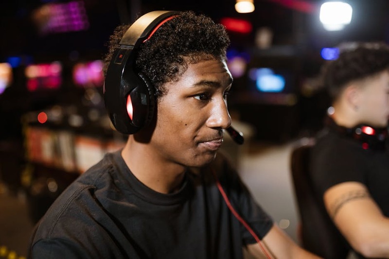 Ein modernes, kabelloses Gaming Headset mit RGB-Beleuchtung auf einem Schreibtisch mit PC und Monitor.