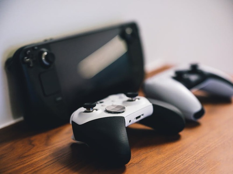 Drei Gaming-Konsolen (PS5, Xbox Series X, Nintendo Switch) auf einem Tisch