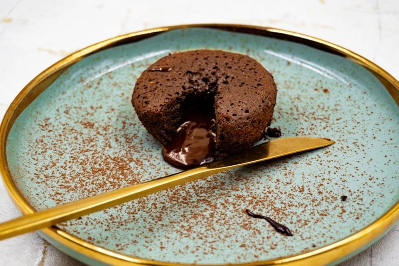 A rich dark chocolate lava cake with a scoop of vanilla ice cream and a cup of dark roasted coffee