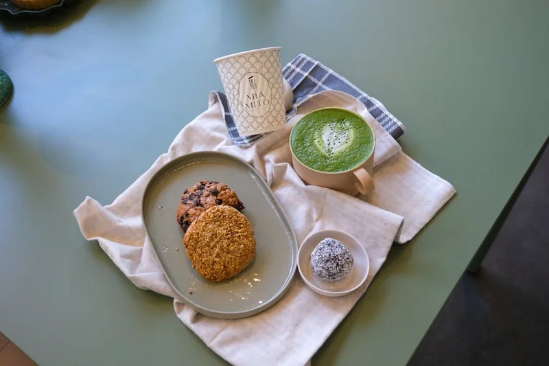 A shot of espresso in a small white cup with two cantuccini cookies on the side
