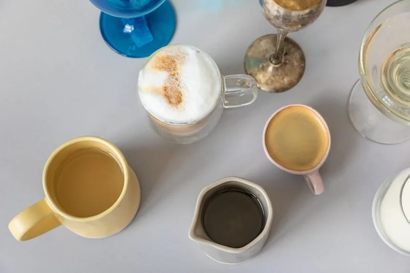 Verschiedene Kaffeegetränke, darunter ein Flat White und ein Americano, auf einem Holztisch