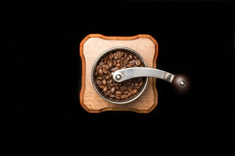 High-quality, freshly roasted coffee beans next to a manual coffee grinder