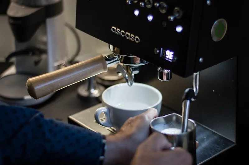 A compact home espresso machine with a visible steaming wand, ready for milk frothing