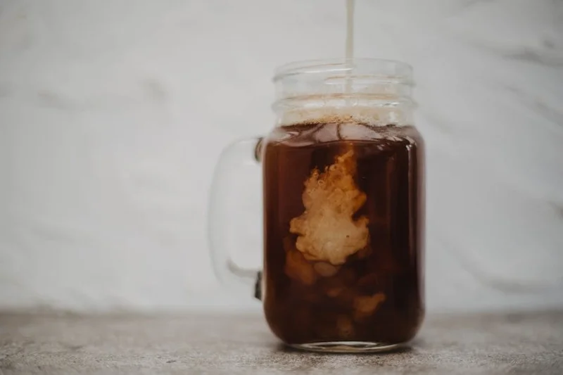 Clear glass jar filled with dark cold brew coffee concentrate, stored in a refrigerator