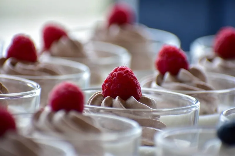 Delicious vegan chocolate avocado mousse in glasses with fresh raspberries