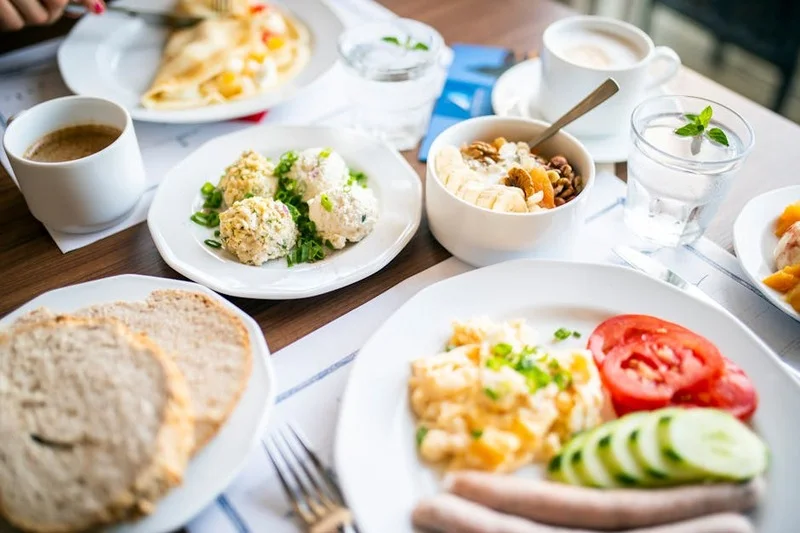 Köstlicher traditioneller deutscher Frühstücksaufstrich mit Rührei, knusprigem Speck, lokalen Käsesorten, Würstchen, Marmeladen und frischen Brötchen