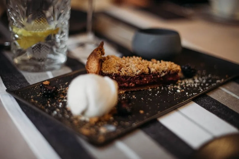 Hot vegan and gluten-free berry crumble served with a scoop of plant-based vanilla ice cream
