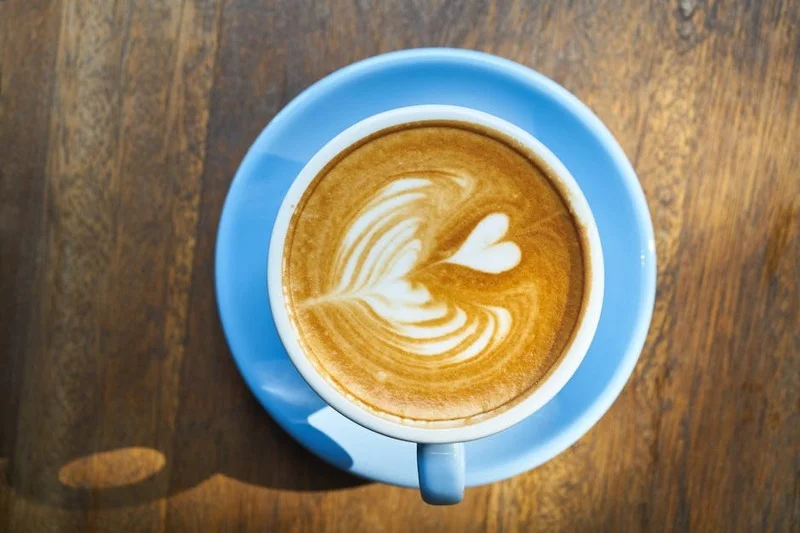A detailed latte art rosette, showing multiple layers and a clean finishing stroke, in a brown ceramic cup