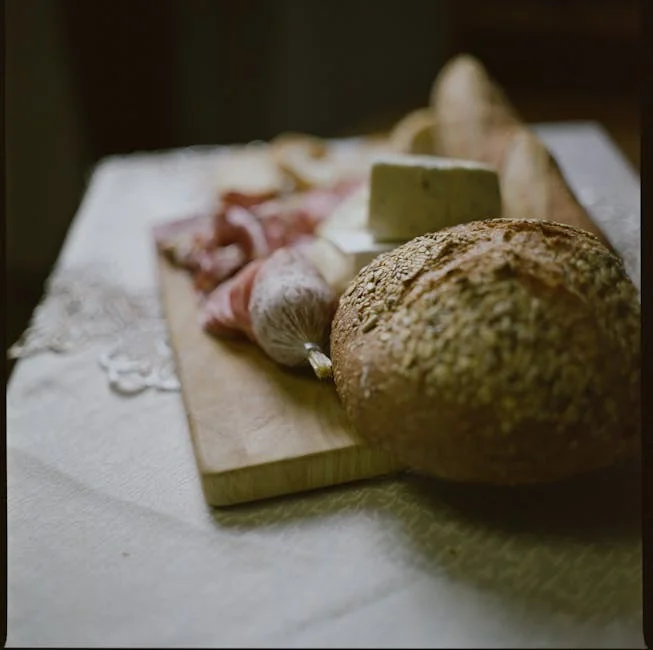 Gourmet-Brunchplatte mit handwerklichem Käse, Wurstwaren, hausgemachten Marmeladen und frisch gebackenem Sauerteigbrot, eine Tasse Spezialitätenkaffee daneben