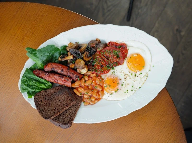 Herzhafte deutsche Brunchplatte mit verschiedenen Würstchen, dunklem Roggenbrot, Senf und Spiegelei in rustikaler Umgebung