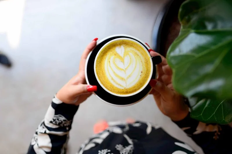 A close-up of hands holding a ceramic mug with a beautiful latte art design, conveying a sense of accomplishment